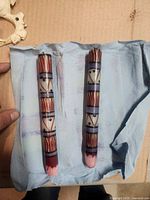 Two hand-painted wax taper candles on blue cloth