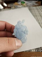 Front view of light blue translucent Laughing Buddha resin figurine held in hand