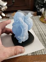Front view of light blue resin Laughing Buddha on black base