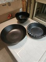 Three black porcelain pieces: pasta bowl, salad bowl, fluted pie dish