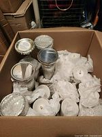 Box shows four mercury glass candlesticks and multiple LED candles wrapped in tissue