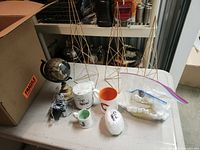 Group shot of all items on table: three wire towers, globe, mugs, demitasse cup, bubble-wrapped cup, bag with scented oil