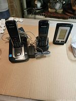 Full lot view showing two Panasonic handsets on their respective charging cradles, power adapter, and La Crosse temperature station