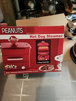 Front of retail box showing Peanuts Snoopy red hot dog steamer and capacity information
