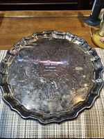 Top view of scalloped round tray showing engraved decoration and tarnish