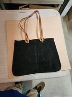 Front view of black suede tote showing rectangular shape and straps
