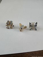 front view of three brooches showing motifs and rhinestones