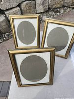 Three matching gold metal frames displayed upright outdoors
