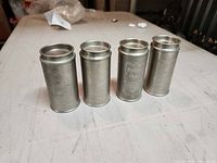 Front view of four brushed metal spice canisters with lids off showing embossed labels