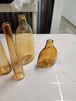 Front view of four amber glass vases showing varying shapes and heights
