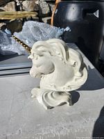 Front view of cream iridescent ceramic unicorn bust with gold horn on sculpted base
