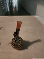 Overall view of pink glass vase with metal overlay on table