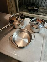 Overall view of two saucepans with lids and shallow casserole