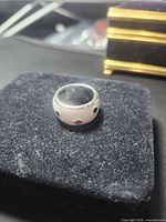 Front view of ring on display pad showing white enamel surface and colored dots