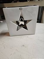 Front view showing white ceramic square vase with star cut-out and Abbott label