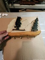 Front angled view of wooden key holder showing bear skiing scene and four pegs