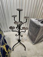 Full view of wrought iron floor candelabra showing six arms and tripod base