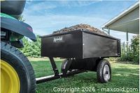 Assembled black Agri-Fab dump trailer hitched to tractor, filled with yard debris, side and rear view