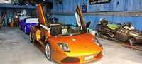 Orange Lamborghini with gullwing doors raised inside detailing shop