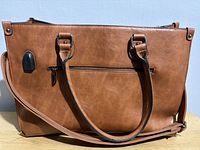 Front view of LOVEVOOK cognac brown faux-leather laptop tote showing USB port, exterior zipper, handles and crossbody strap