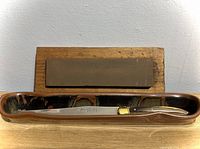 Saber resting in ceramic tray with oilstone and wood base behind