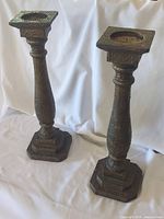Full view of both tall candle holders standing side by side