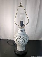 Full lamp showing porcelain body, harp, finial