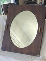 Full view of mirror with wooden frame and oval glass