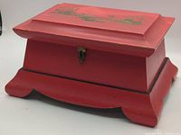 Closed red wooden jewelry box showing painted lid and base