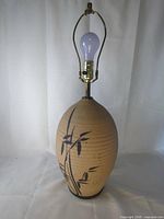 Full lamp showing pottery base, harp, socket, bulb