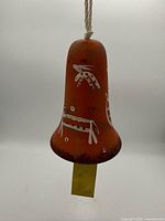 Front view of terracotta bell showing painted Southwestern motifs and hanging cord