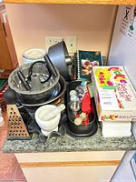 Lot overview showing pans, mortar & pestle, books, grater, cookie cutters, boxed mold kit
