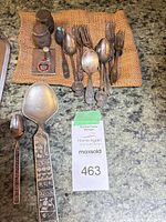 Group view on countertop showing serving spoon, small spoons, forks, shakers, case