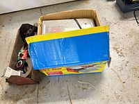 Boxed tile saw beside open metal toolbox
