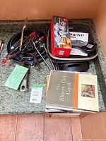 Assorted pans, utensils, burger press box and cookbooks on countertop