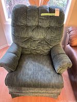 Front view of tufted green swivel armchair showing upholstery, rolled arms, seat and back cushions