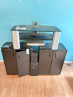 Front view of TV stand with cabinets open, subwoofer, speaker, DVD player, remote