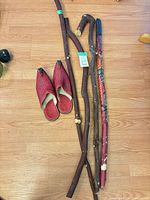Overview of four walking sticks and red slippers on floor