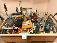 Workbench with drill, propane cylinder, levels, screwdrivers, tape, hardware jars