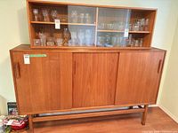 Full view of teak sideboard with hutch showing sliding doors and glass display