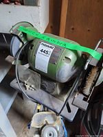 Full view of green 6-inch bench grinder on pedestal stand with accessories visible