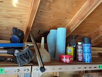 Shelf with brushes, squeegee, funnel, towel rolls, chemicals visible