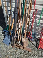 Group of long-handled yard tools leaning against wall