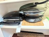 Breville wok with lid, George Foreman grill, drip trays, cutting board on shelf