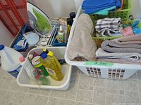 Laundry baskets with towels, tub of cleaning liquids, steam iron