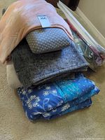 Stacked bedding showing comforter, throw, decorative pillow, and linens bag