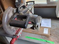 Overall view showing Craftsman miter saw with clear blade guard and handle, manual beside unit
