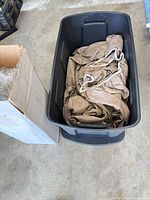 Open black tote with tan car cover inside next to cardboard box