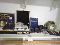 Shelf view showing mahjong set, puzzle box, coin album, binoculars, tape dispenser and accessories
