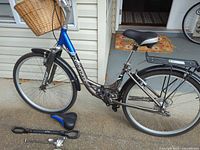Entire bicycle with spare saddle and cable lock on ground